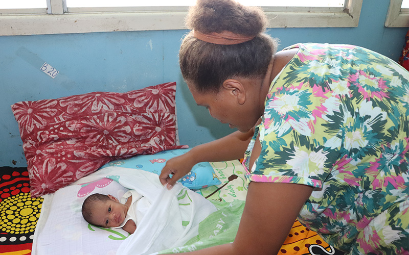 Mary Tuhaika wrapping her son Jake in a baby swaddle blanket.