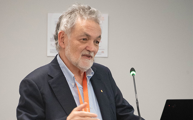 Professor Guy Marks AO speaking behind a standing microphone