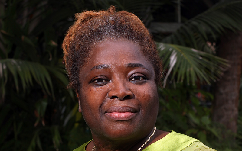 Dr Tamara Kwarteng OAM looking at the camera, wearing a green outfit.