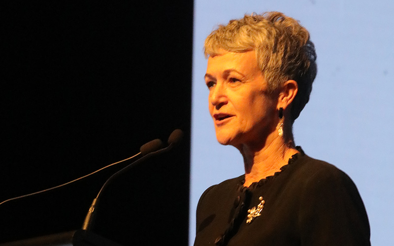 Caroline Homer speaking into a mic at a podium